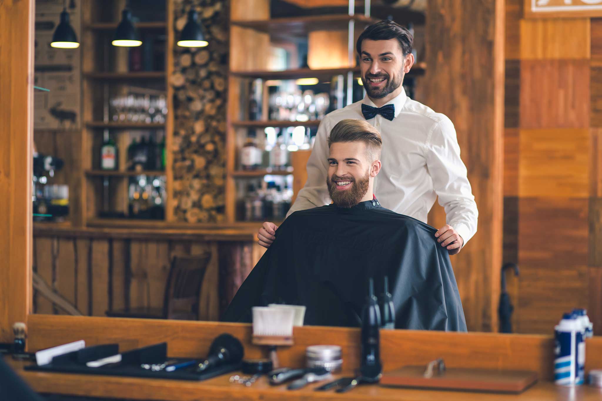 Abbildung - Ein Mann sitz fröhlich beim Friseur und lässt sich die Haare schneiden.