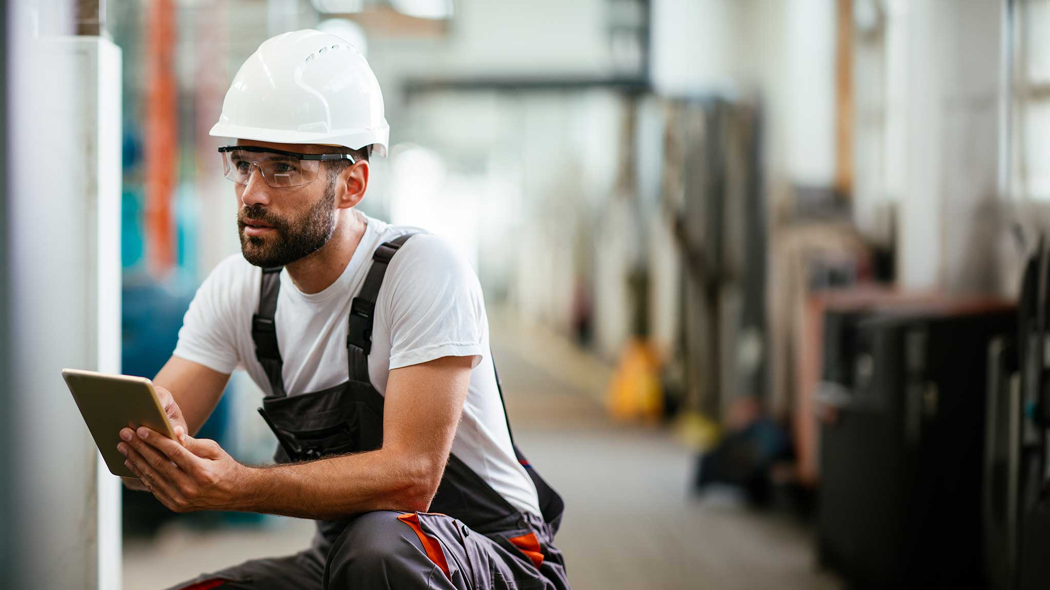 Abbildung - Ein Fabrikarbeiter, der die Produktion in der Fabrik mit einem Tablet kontrolliert.